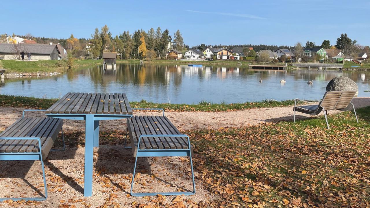 Picknicktisch im Vordergrund, Badeteich im Herbst